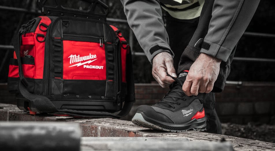 Person knyter Milwaukee Flextred låg textilsko