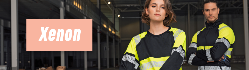 En man och en kvinna står med armarna i kors i mörk industriell miljö och båda klädda i arbetskläder från Jobman. Texten &quotXenon" ligger mot en rosa ruta.