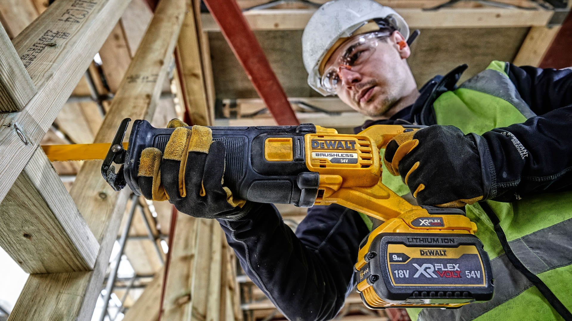 Person i byggmiljö och arbetskläder sågar i en träkonstruktion med en batteridriven tigersåg från Dewalt, modell XR FLEXVOLT 54V.  